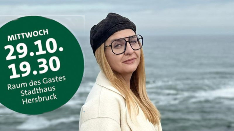 Referentin Inna Perduhowa mit weißer Jacke, schwarzer Brille und Mütze am Strand